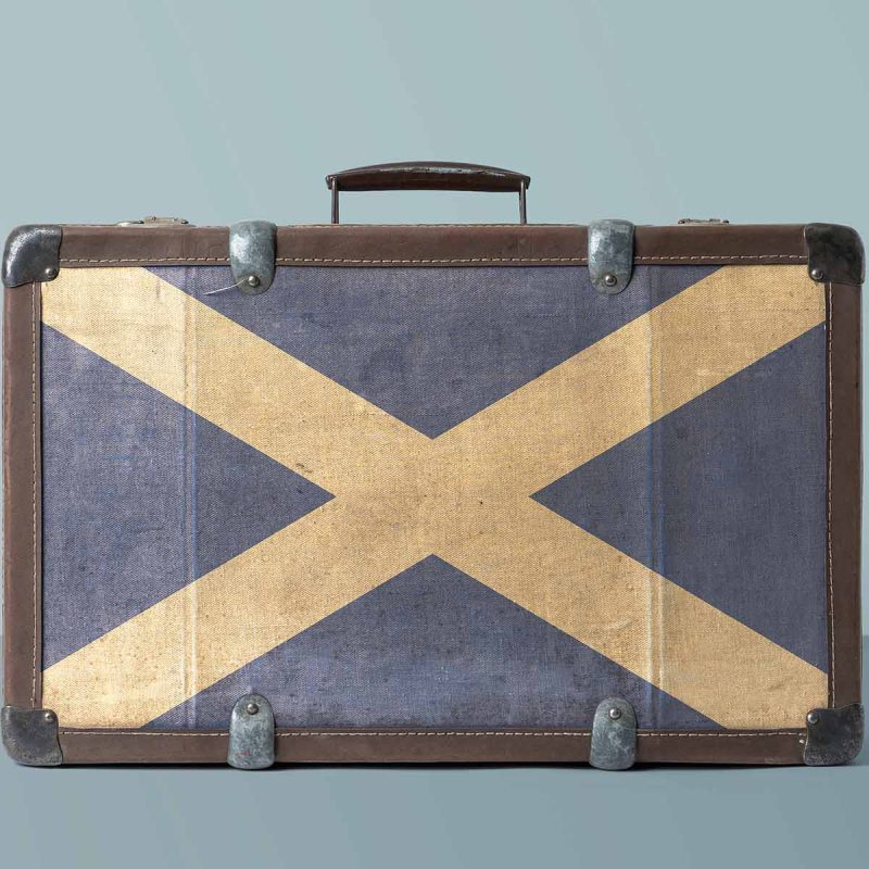An old fashioned suitcase with the Scottish flag on it, ready for visiting Scotland.