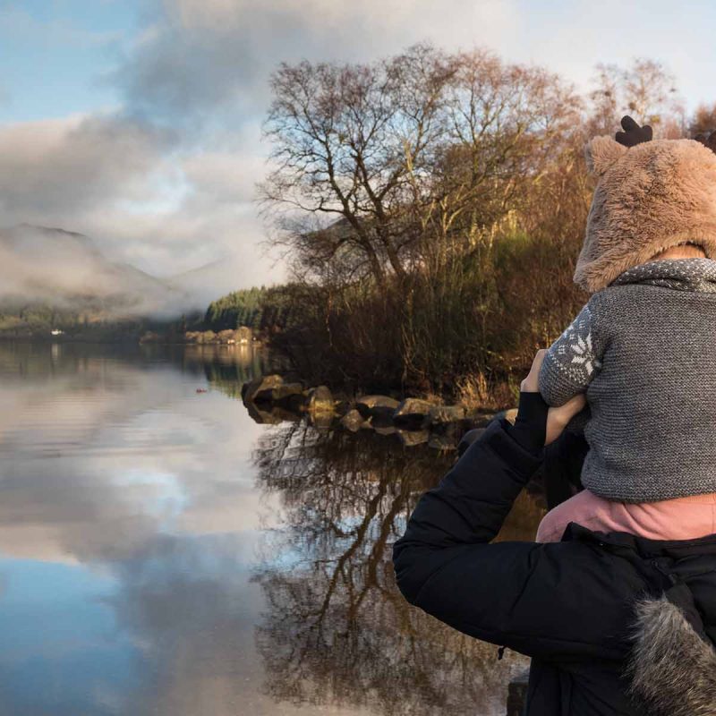A child on a lady's shoulders at Loch Lomond.