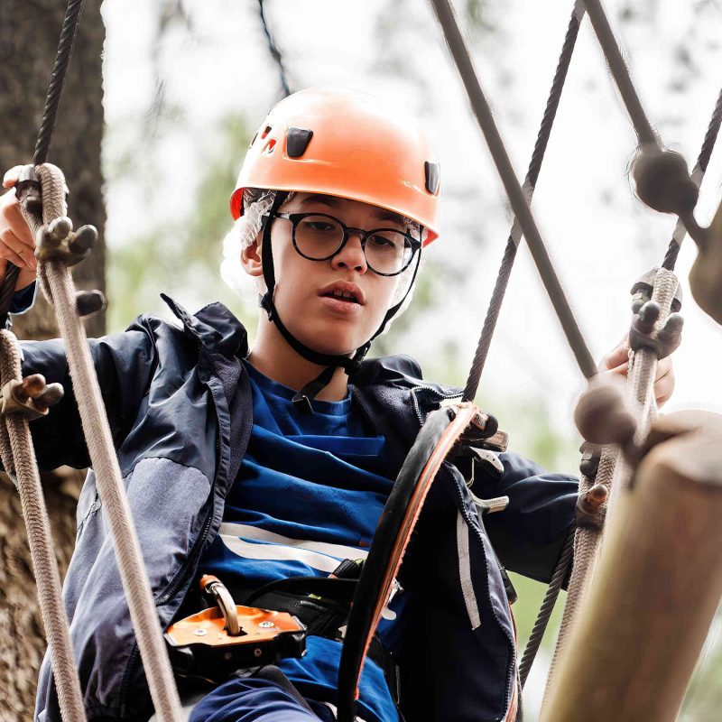 Boy taking part in an aerial course challenge in the trees