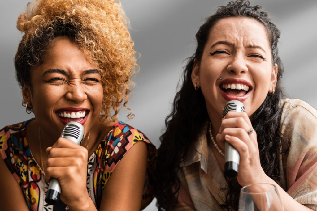 Two women singing into mics at a party