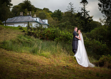 A bride and groom in the grounds of Stuckgowan by Loch Lomond with Stuckgowan in the background