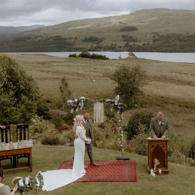 A bride and her groom getting married outside next to Loch Tay at a wedding at Stucktaymore next to Loch Tay